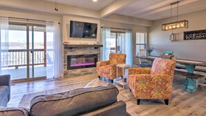 A spacious living room with a fireplace, comfortable seating, a dining area, and a large TV. - Lampe Retreat w/ Pool Access - Walk to Lake! (Lampe)