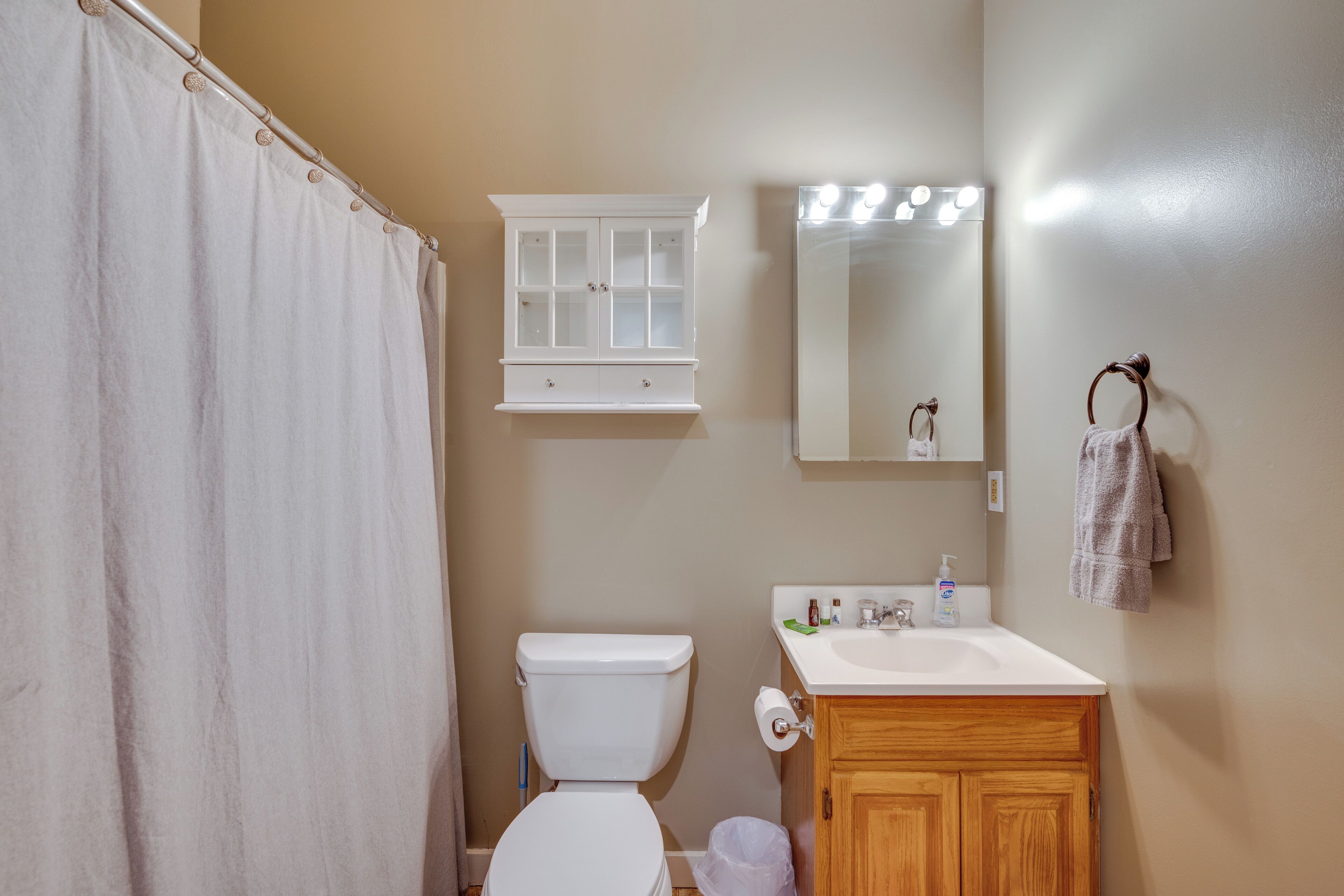Une salle de bain équipée d’une douche avec rideau, de toilettes, d’un meuble-lavabo avec miroir et d’un évier.
