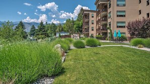 A multi-story building with balconies, a well-maintained lawn, and a view of mountains in the background. - Manson Condo w/ Pool Access - Near Marina and Town (Manson)