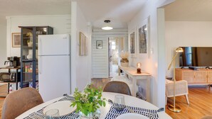 A modern kitchen with a refrigerator, microwave, and dining area with a table set for two. - Mid-century Modern Fayetteville Home Close to Town (Fayetteville)