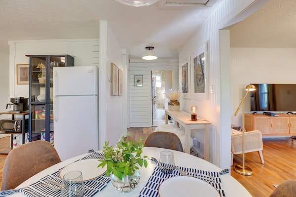 Une cuisine moderne équipée d’un réfrigérateur, d’un four à micro-ondes et d’un coin repas avec une table dressée pour deux personnes.