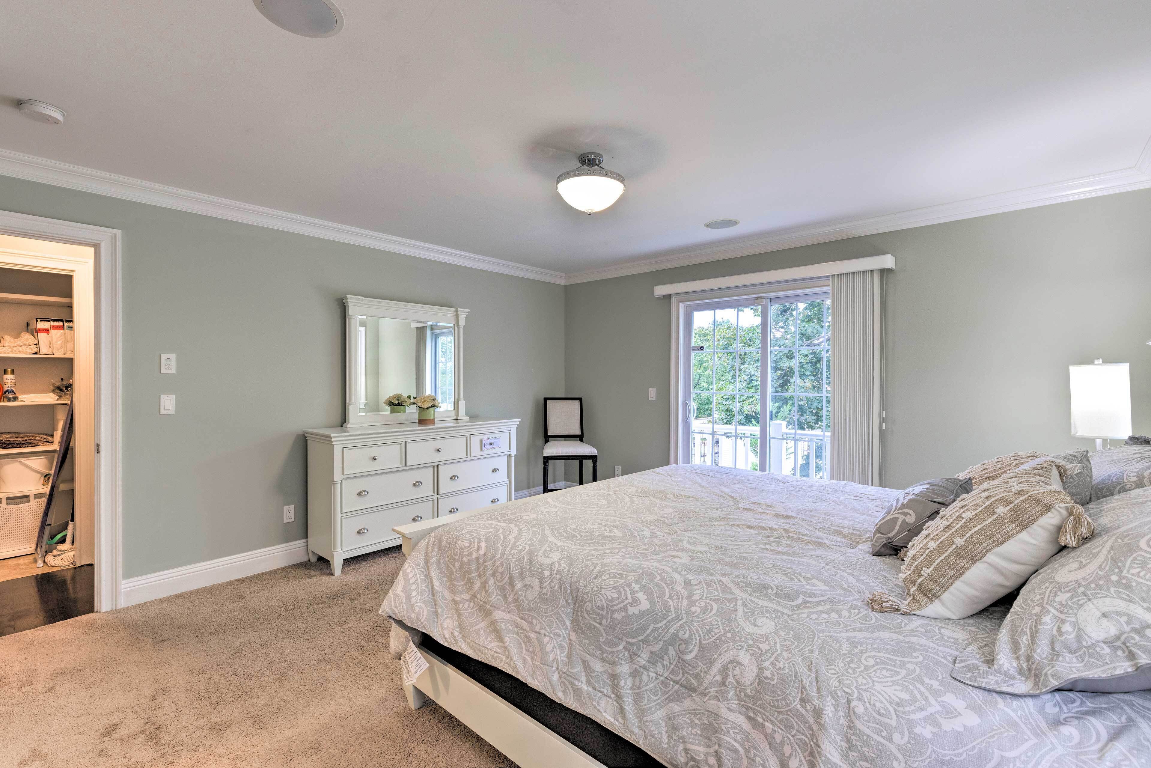 A bedroom with a large bed, a dresser, a chair, and a closet.