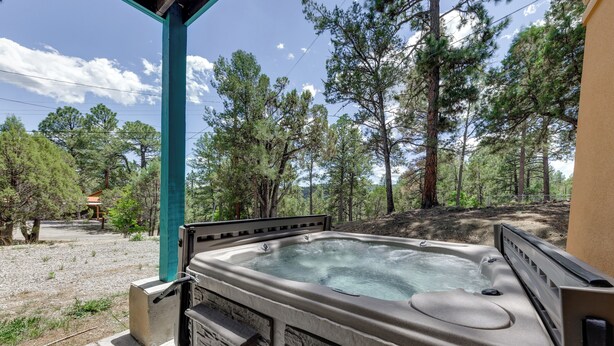 Un bain à remous installé dans un cadre naturel, avec une terrasse en bois et un mur en pierre.
