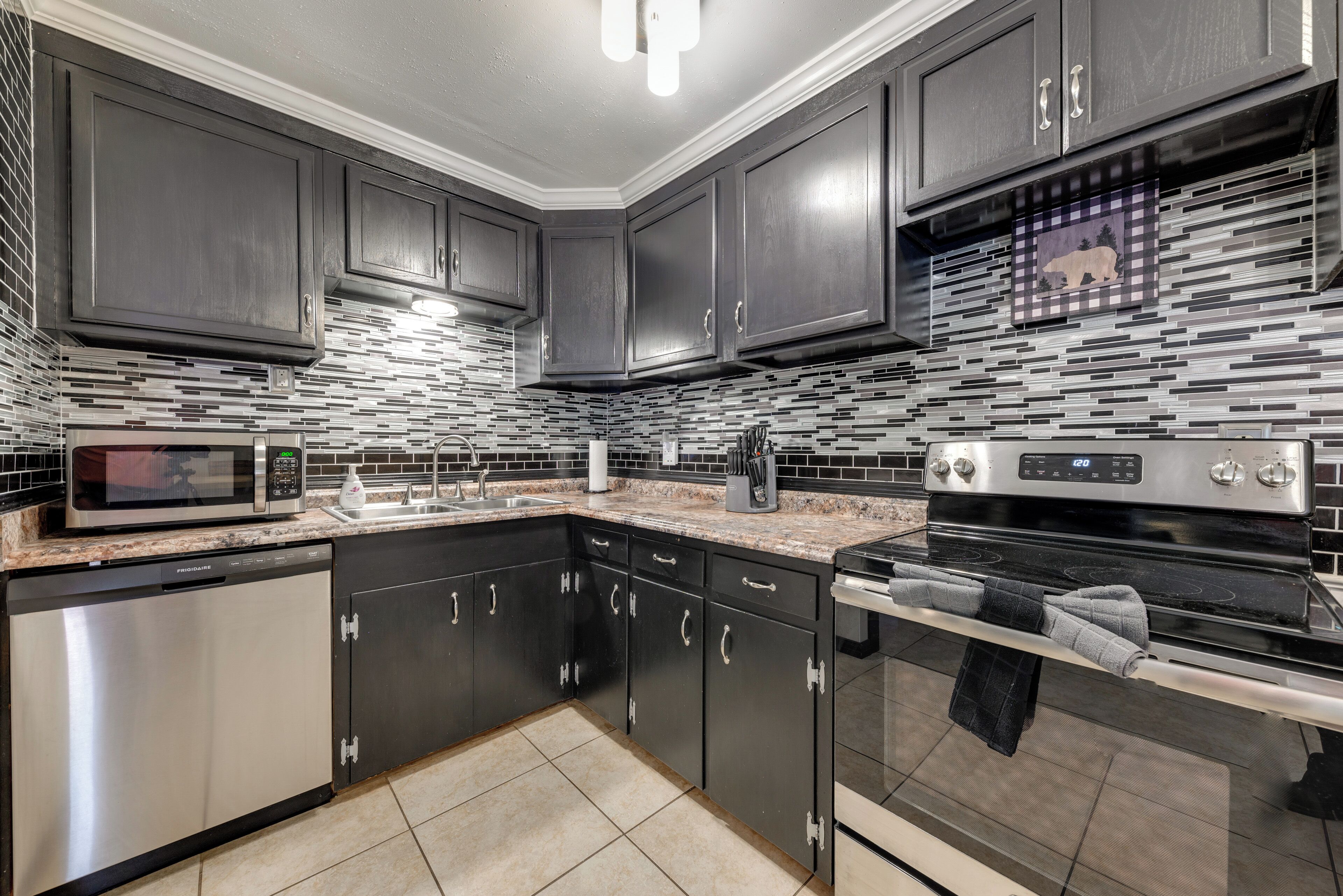 A modern kitchen with dark cabinets, a microwave, a stove, and a dishwasher.