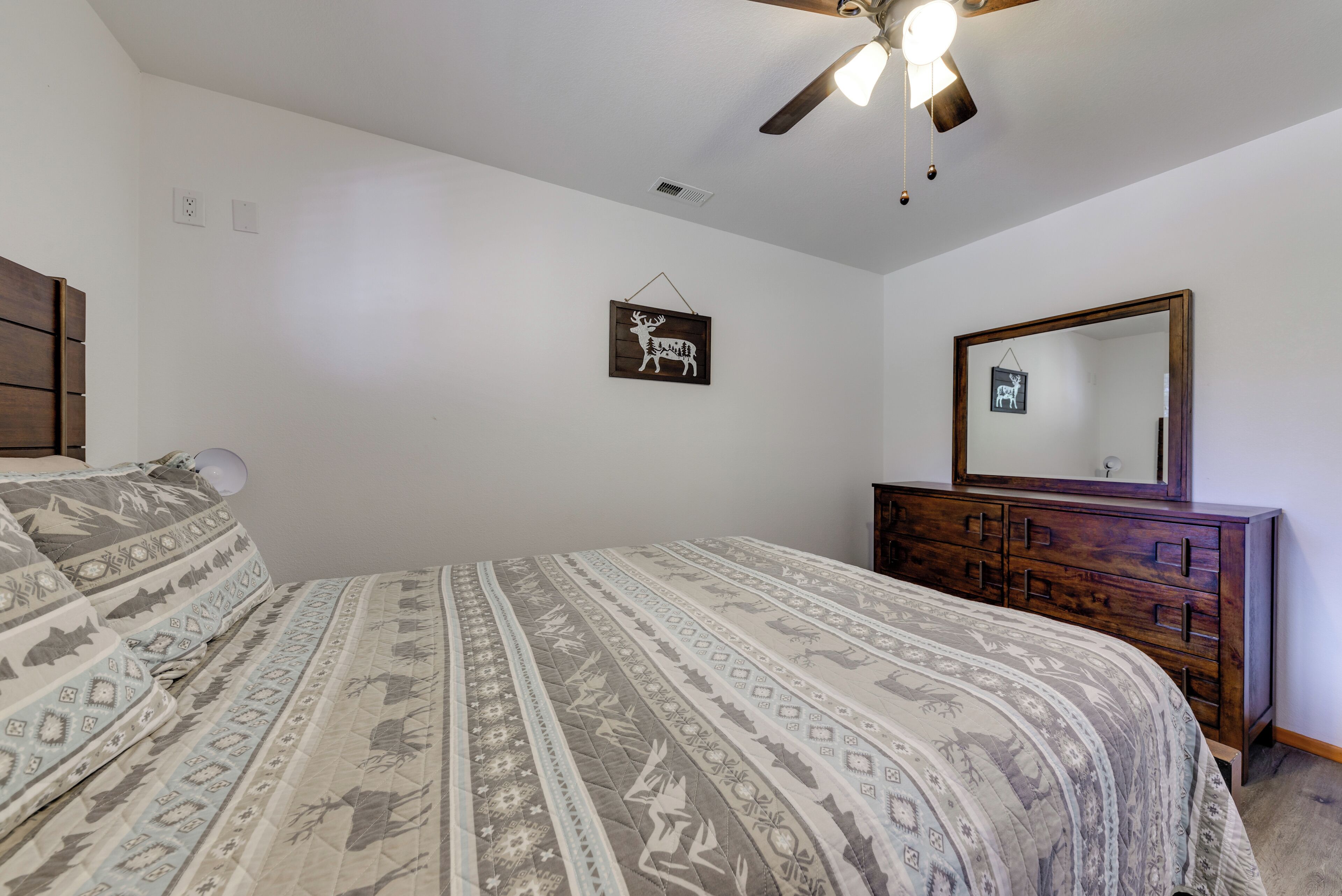 Un dormitorio con cama, cómoda, ventilador de techo y espejo en la pared.