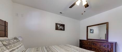 Un dormitorio con cama, cómoda, ventilador de techo y espejo en la pared.