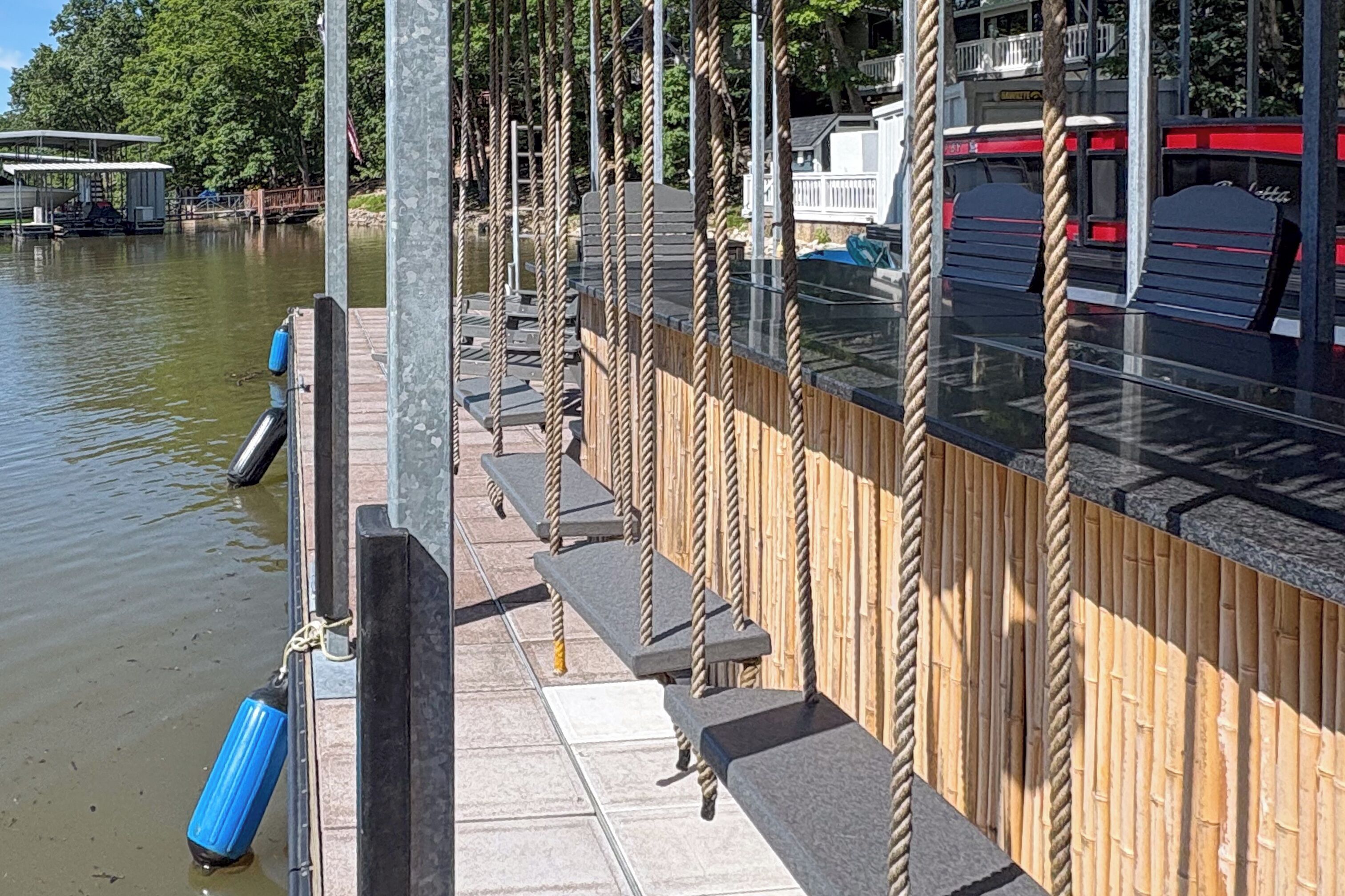 Une jetée bordée d’une rangée de bancs et délimitée par une barrière faite de cordes.