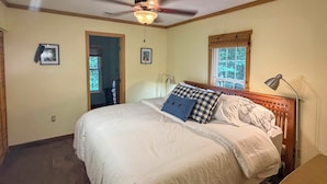 A bedroom with a bed, a ceiling fan, a window with blinds, and a door.