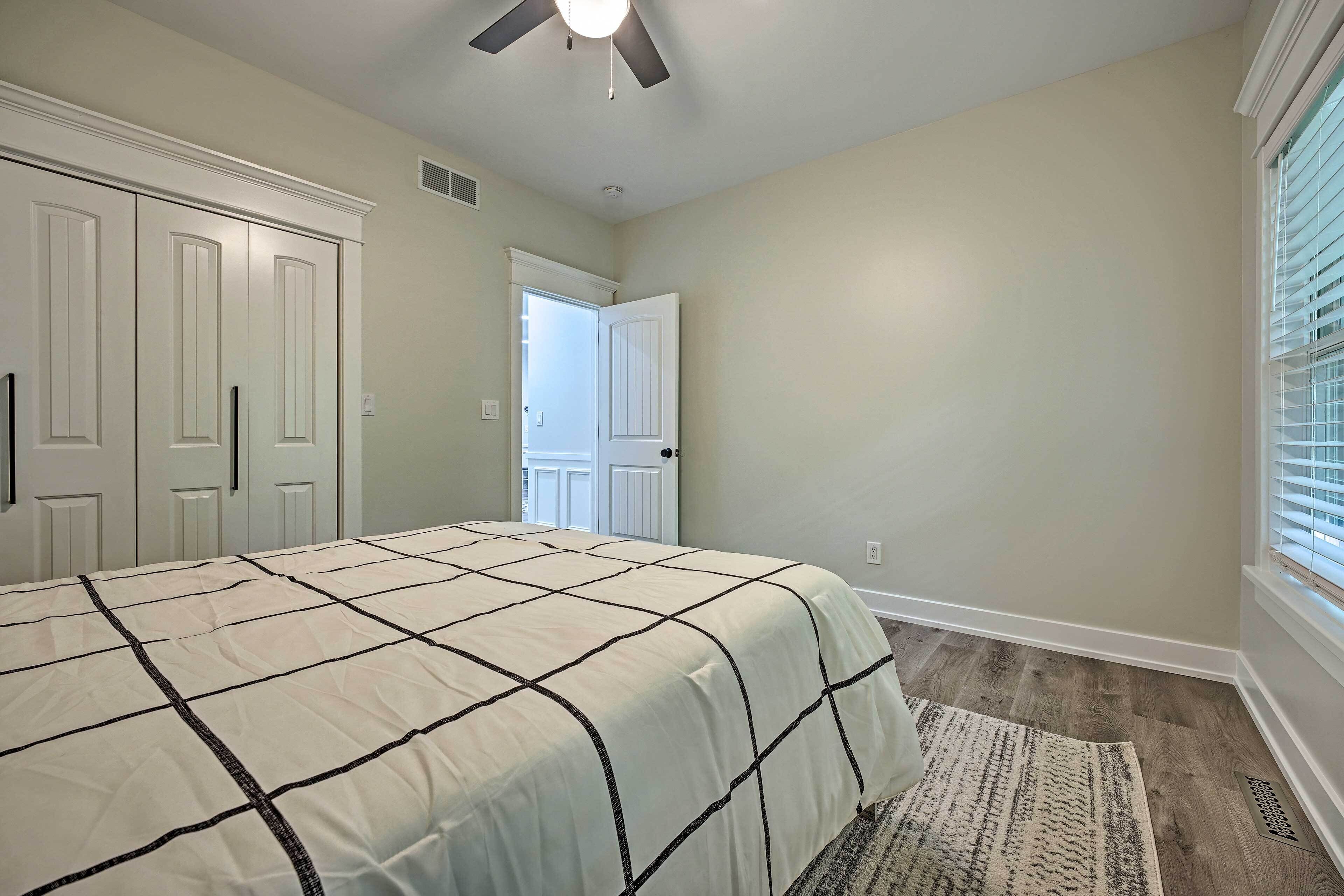 A bedroom with a bed, a ceiling fan, and a window with blinds.