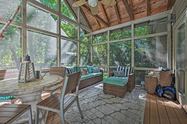 A covered outdoor patio with wooden furniture, large windows, and a ceiling fan. - Luxury Family Home w/ Deck, Swim Spa & Grill! (New Buffalo)