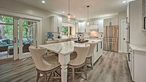 A modern kitchen with white cabinetry, a marble island, and pendant lighting.