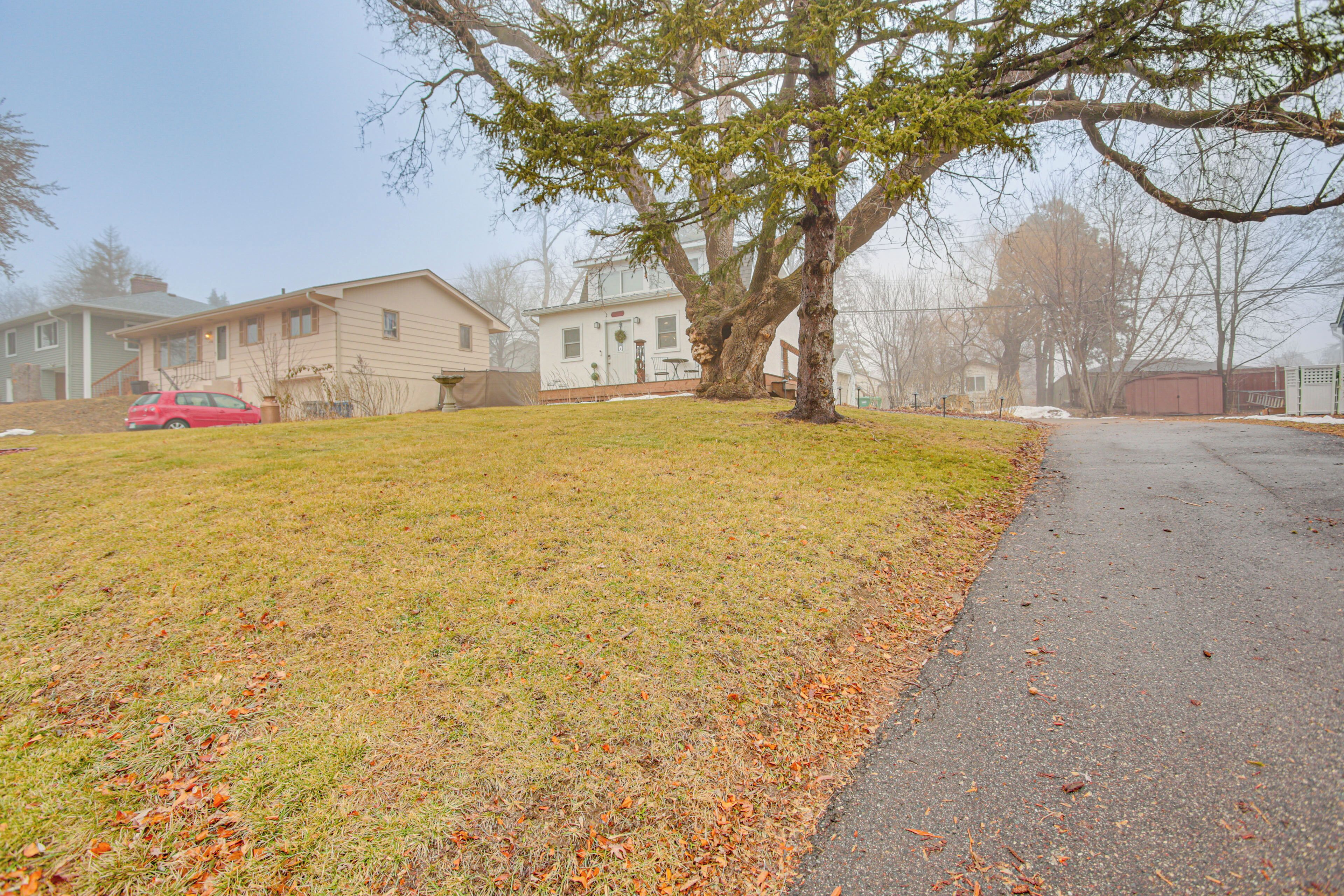 A residential area with houses, a tree, and a red car parked on the street.