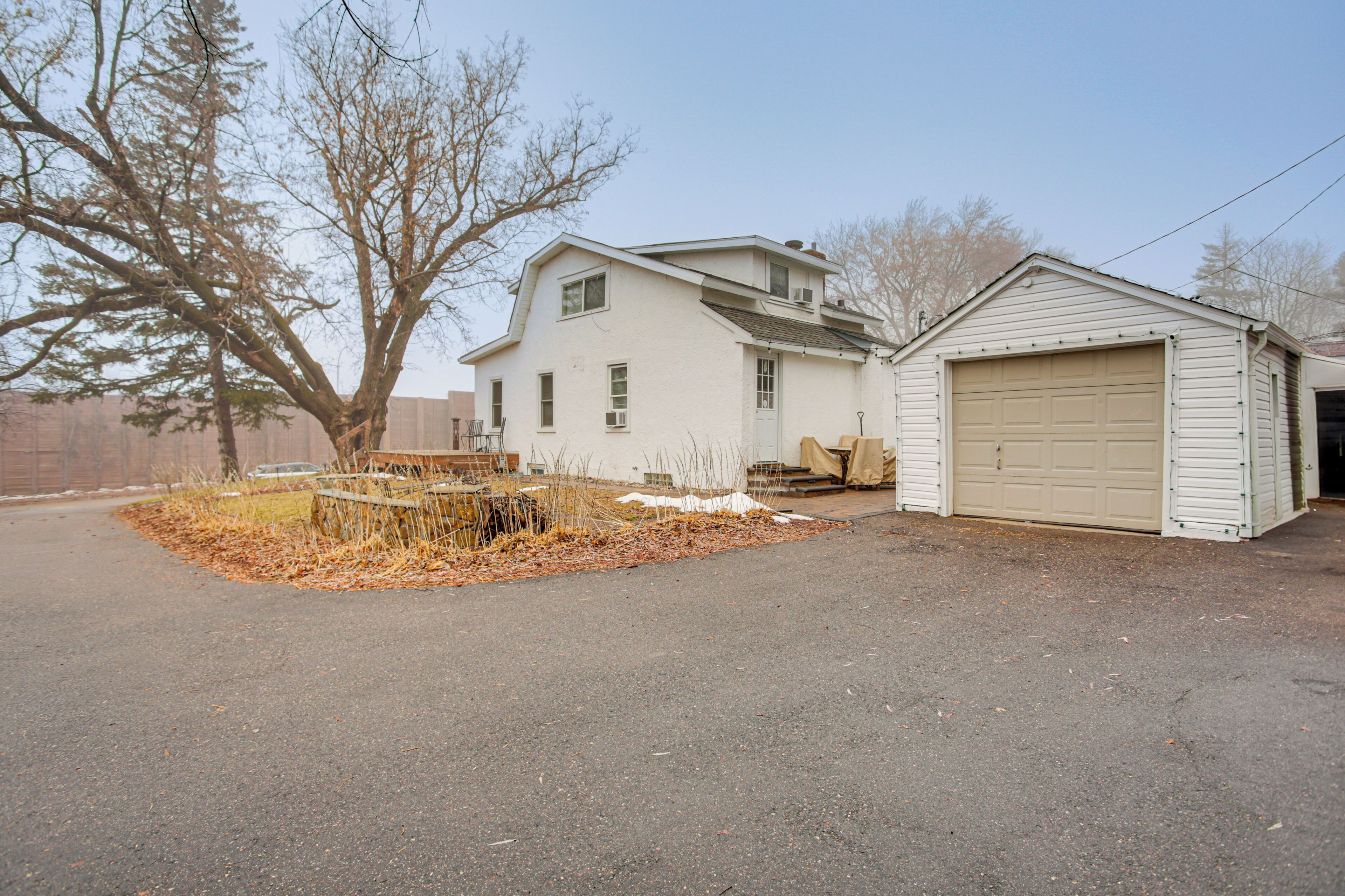 A two-story house with a garage, a large tree in the yard, and a wooden fence.