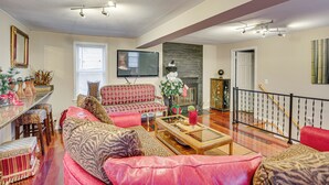A spacious living room with a red sofa, patterned cushions, a wooden coffee table, and a television mounted on the wall. - Families w/ Pets! Home 8 Mi to Dtwn Minneapolis (Golden Valley)