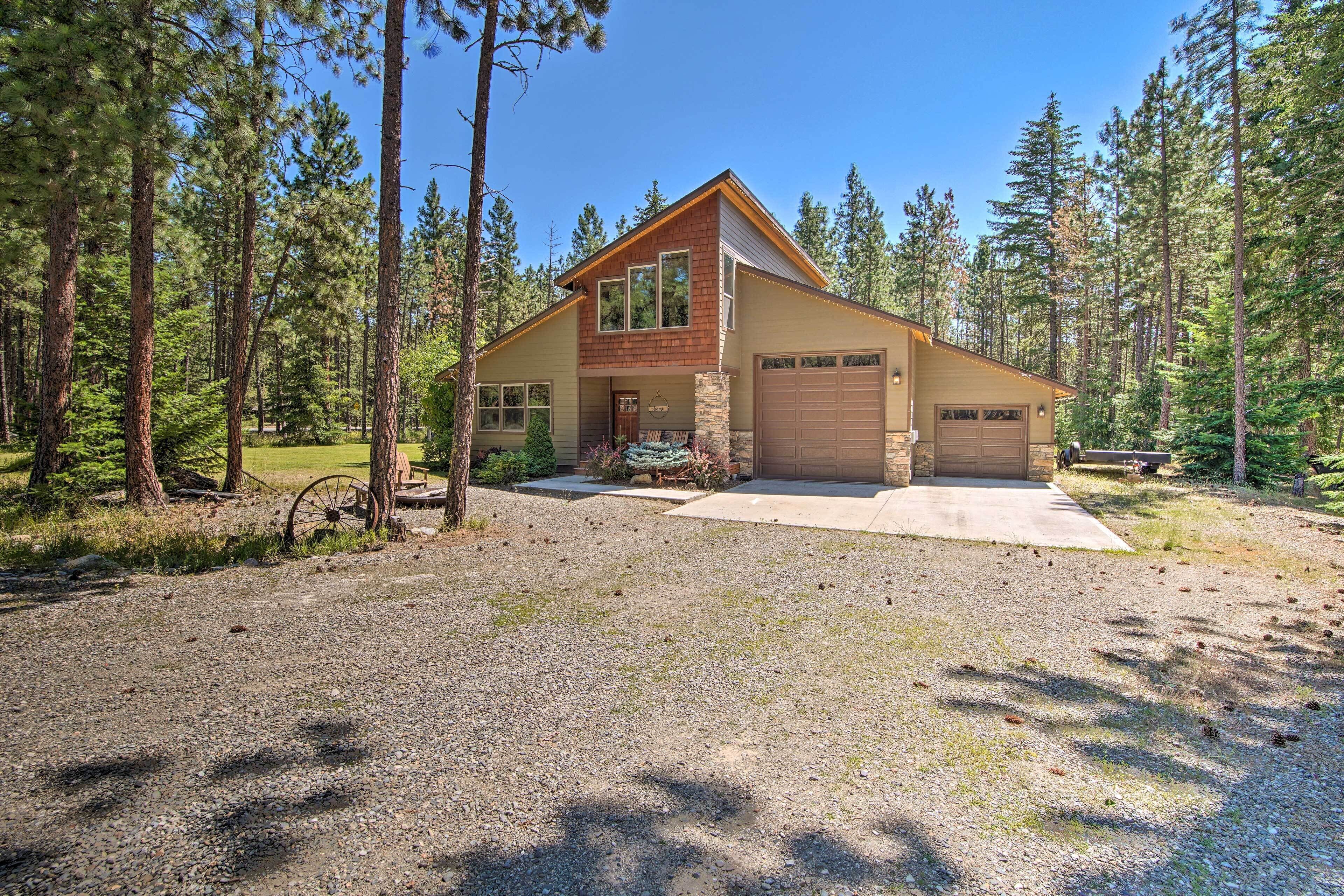 A two-story house with a stone foundation, a large garage, and a gravel driveway.