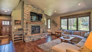 A spacious living room with a stone fireplace, a large TV mounted above it, and a comfortable seating area with a sofa and a coffee table. - Modern-rustic Ronald Getaway: Hot Tub, Grill! (Cle Elum)