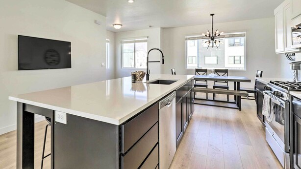 A modern kitchen with a central island, stainless steel appliances, and a dining area with benches. - Modern Townhome - 8 Mi to Thanksgiving Point! (American Fork)