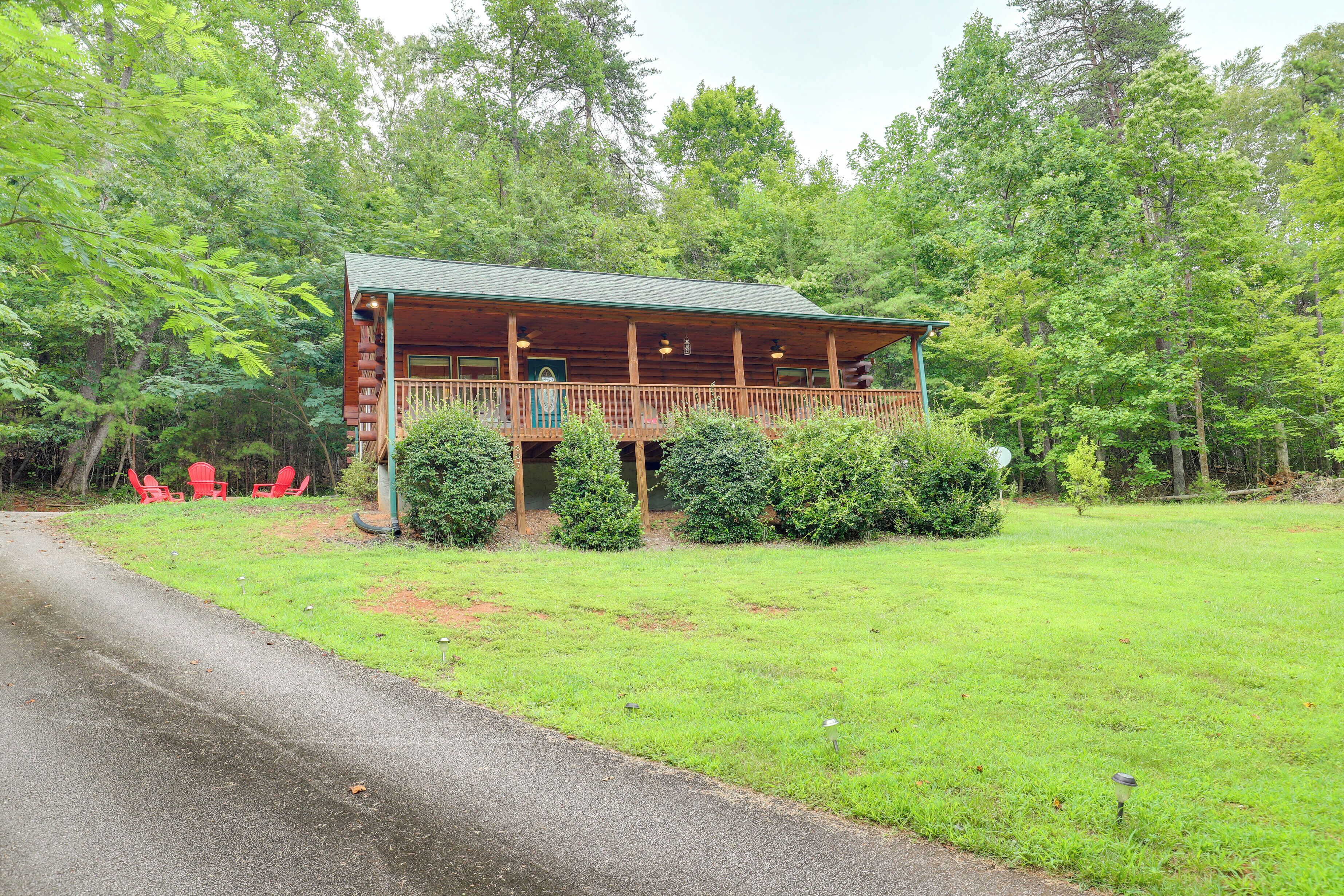 Una cabaña de madera con balcón, rodeada de exuberante follaje y árboles.