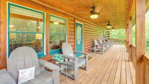 A covered porch with wooden chairs and tables, large windows, and a ceiling fan. - Hot Tub Soaks! 'moonshine Manor' Near Lake Lure (Lake Lure)