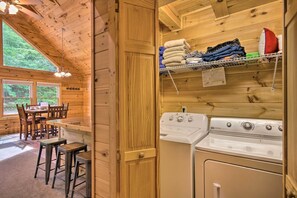 L’intérieur d’une cabane en bois comprend un coin repas, des tabourets de bar et un lave-linge.