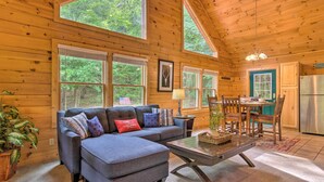 A cozy cabin interior with a sofa, dining table, chairs, and a kitchen area. - Hot Tub Soaks! 'moonshine Manor' Near Lake Lure (Lake Lure)