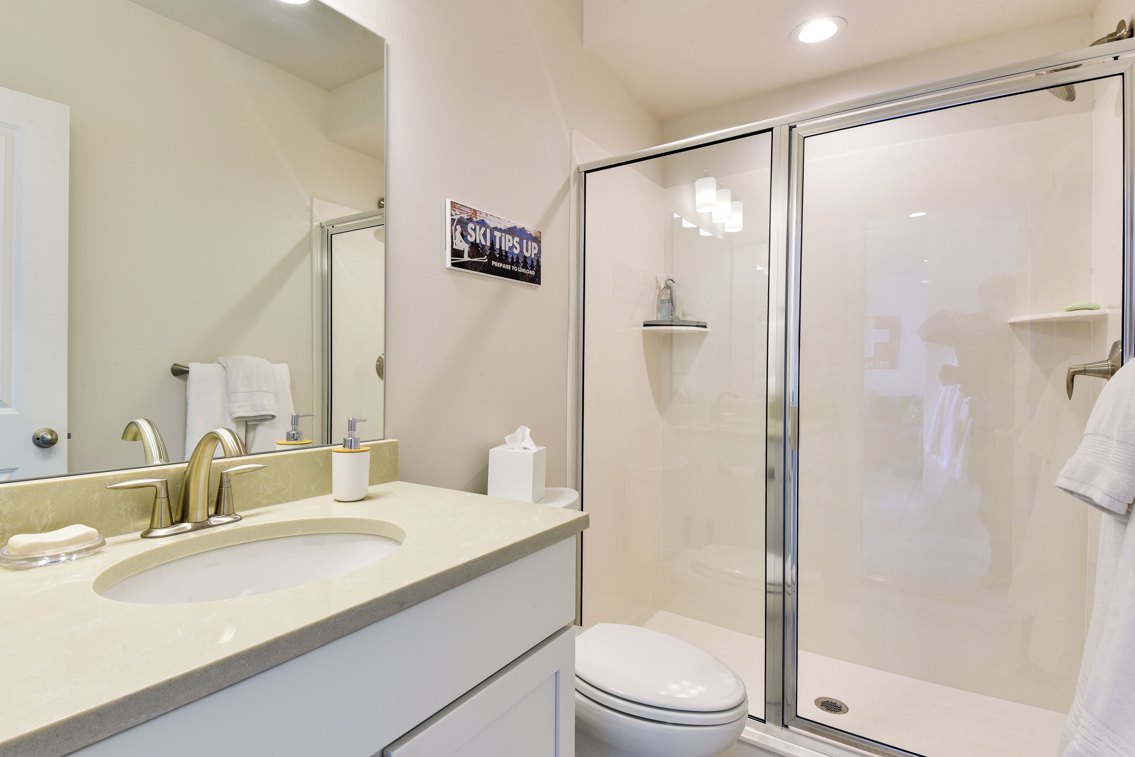 A modern bathroom with a sink, mirror, and a glass shower enclosure.