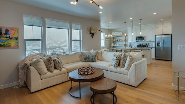 A modern living room with a sectional sofa, a coffee table, and a dining area with a kitchen in the background. - Hot Tub: Heber City Home 15 Mi to Park City! (Heber City)