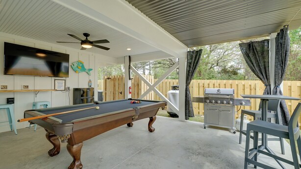 A pool table with a ceiling fan, a TV mounted on the wall, and a barbecue grill outside. - Modern Home w/ Rooftop Deck, Walk to Beach! (Carolina Beach)