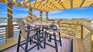 En træterrasse med pergola, udendørs møbler og udsigt over det omkringliggende landskab.