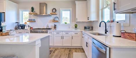 A modern kitchen with white cabinetry, a central island, a built-in oven, and a dishwasher.