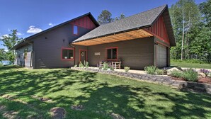 A modern two-story house with a garage, a covered patio, and a well-maintained lawn. - Modern Lakeside Chalet on Crow Wing Chain w/ Dock! (Nevis)