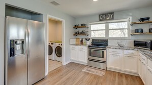 A modern kitchen with stainless steel appliances, white cabinetry, and wooden flooring. - Modern Flower Mound Home < 2 Mi to River Walk (Flower Mound)