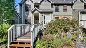 A two-story house with a wooden deck and a stone foundation. - Scenic Views & Trail Access! Blue Ridge Mtns Condo (Burnsville)