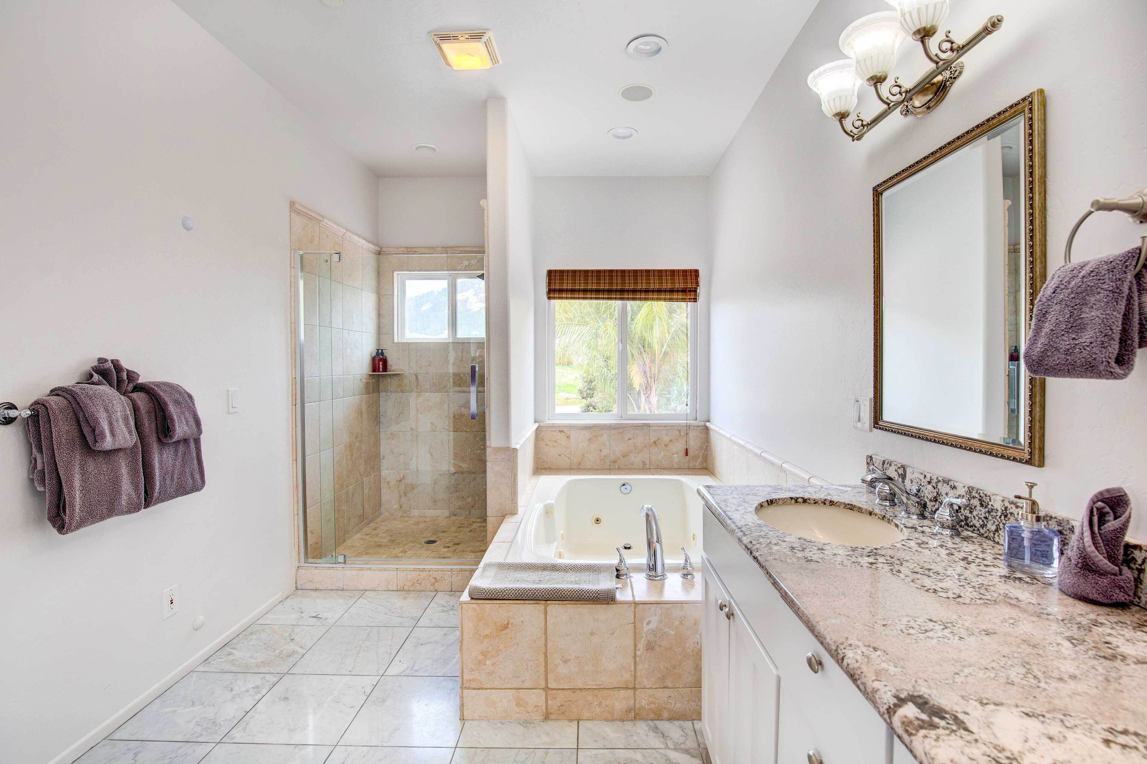 Un baño moderno con ducha de vidrio, una bañera amplia y un tocador con lavamanos y espejo.