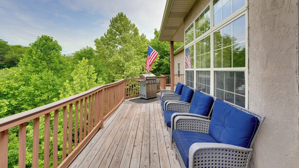 A wooden deck with wicker furniture and an American flag. - 4 Mi to Branson Landing: Huge Home w/ Game Room! (Branson)