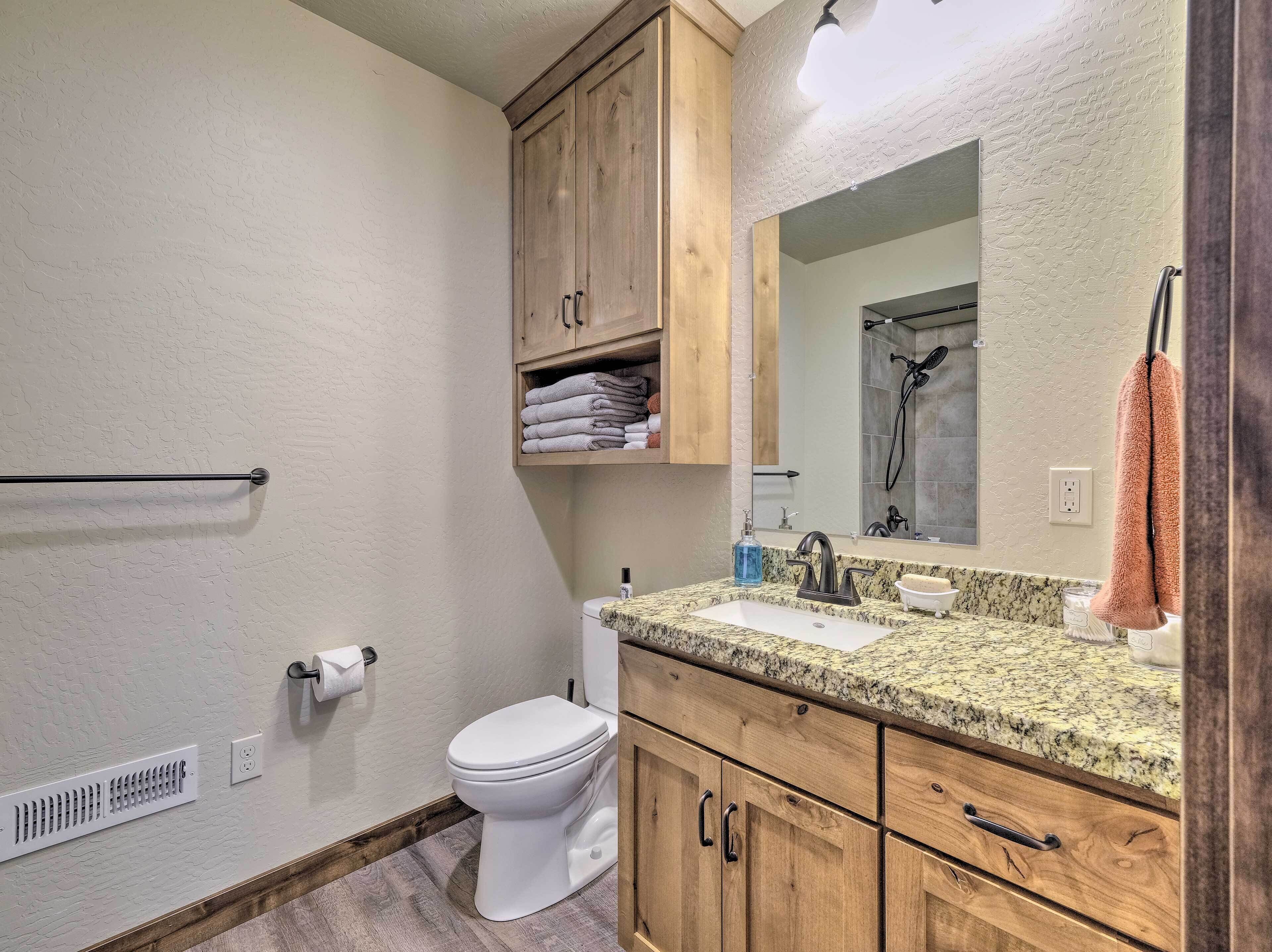 Une salle de bain comprenant des toilettes, un lavabo, des meubles en bois, un porte-serviettes et un miroir.