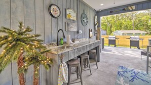 Eine Küche mit Holzwand, Barhocker, Deckenventilator und Blick auf einen Hinterhof mit Grill.