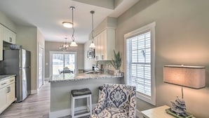 A modern kitchen with a central island, pendant lighting, and a dining area with a view. - Ocean Isle Beach Home w/ Shared Lanai & Grill (Ocean Isle Beach)