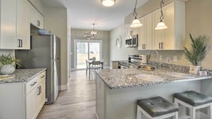 A modern kitchen with granite countertops, stainless steel appliances, and pendant lighting. - Ocean Isle Beach Home w/ Shared Lanai & Grill (Ocean Isle Beach)