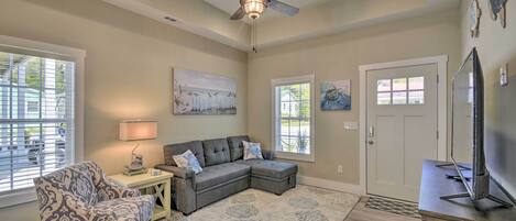 A living room with a sectional sofa, a patterned armchair, a ceiling fan, and artwork on the walls.