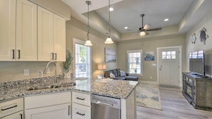 A spacious kitchen with granite countertops, white cabinetry, and a dishwasher. - Ocean Isle Beach Home w/ Shared Lanai & Grill (Ocean Isle Beach)