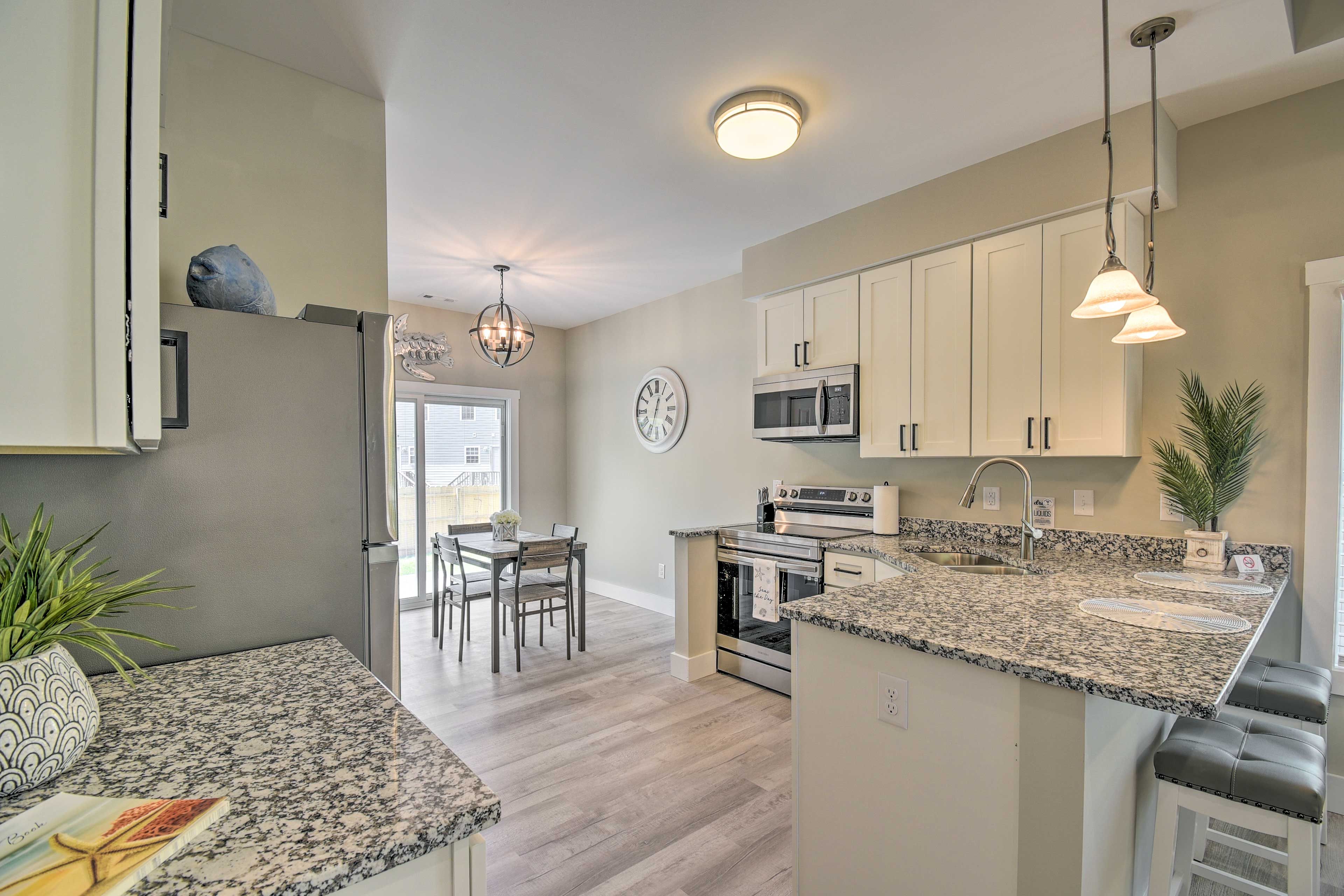 A modern kitchen with granite countertops, stainless steel appliances, and a dining area with a table and chairs.