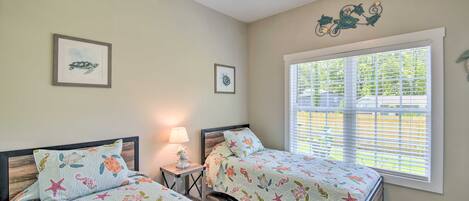 A bedroom with two beds, a ceiling fan, and a window with blinds.