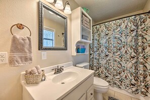 A bathroom with a white sink, a mirror, a towel rack, a toilet, and a shower curtain with a floral pattern. - Pet-friendly 'shady Oaks' Broken Bow Gem w/ Patio! (Broken Bow)