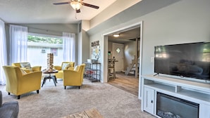 A living room with a fireplace, a television, and two yellow armchairs. - Osage Beach Family Hideaway on No-wake Cove! (Osage Beach)