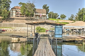 A dock leading to a covered area with a view of a multi-story building with an American flag.