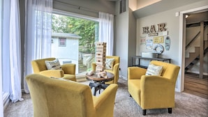 A living room with yellow armchairs, a wooden block tower, and a bar sign on the wall. - Osage Beach Family Hideaway on No-wake Cove! (Osage Beach)