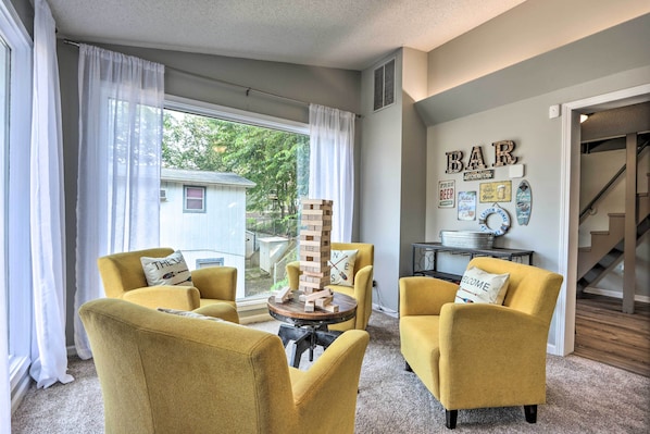 A living room with yellow armchairs, a wooden block tower, and a bar sign on the wall.