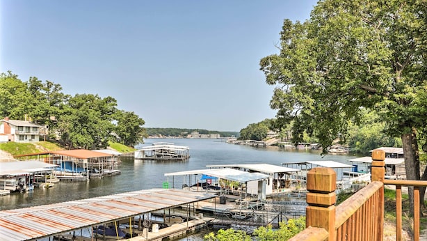 A riverside dock area with boats, wooden walkways, and buildings along the water. - Osage Beach Family Hideaway on No-wake Cove! (Osage Beach)