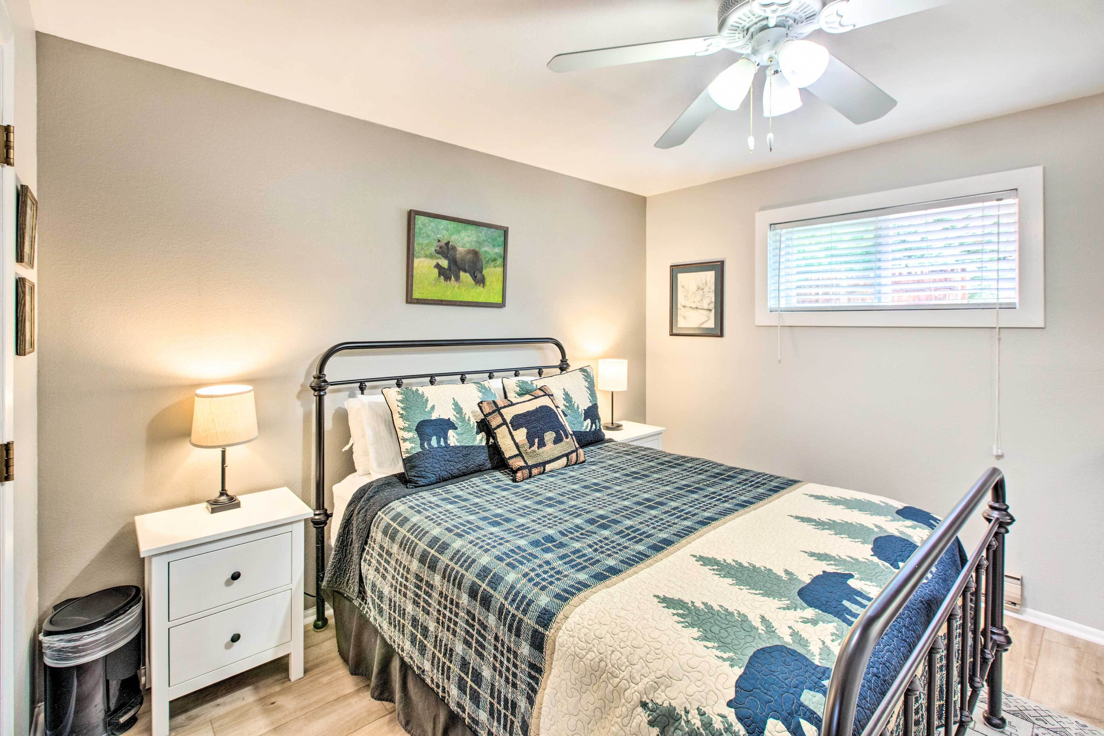 A bedroom with a bed, nightstands, a ceiling fan, and a window with blinds.